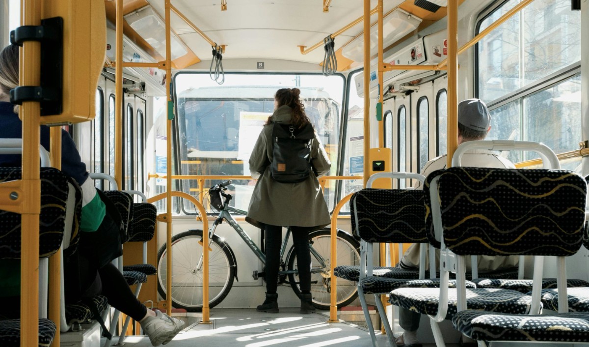 En kvinna står med en cykel på en spårvagn
