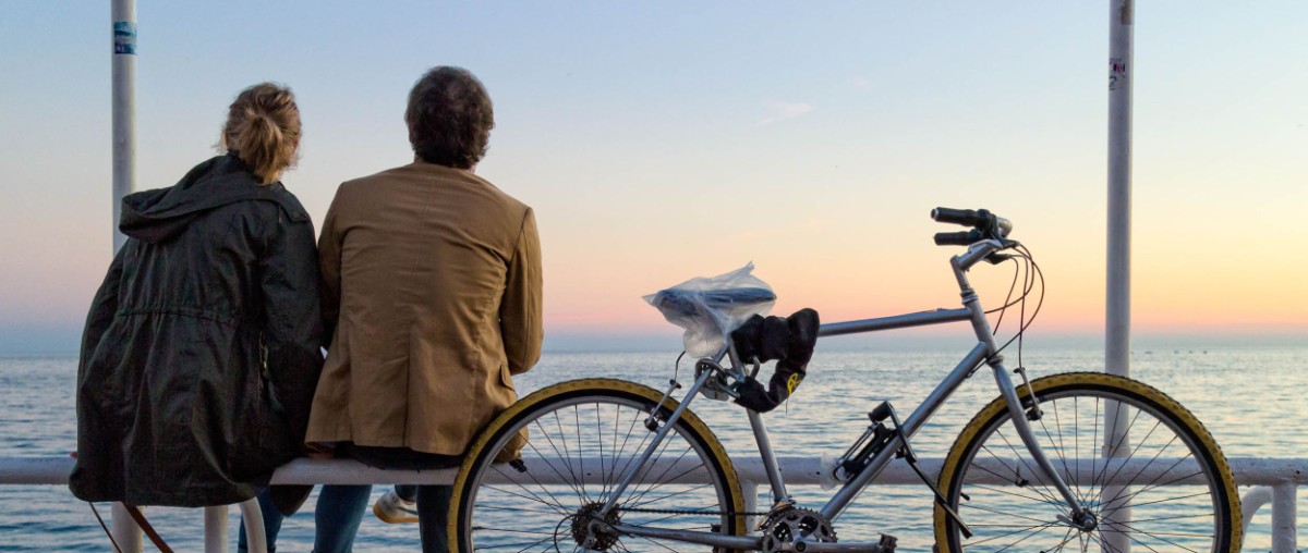 Par som sitter tillsammans vid en cykel och tittar ut över havet