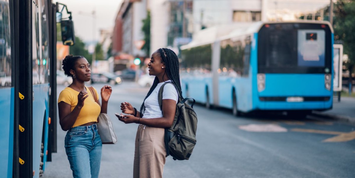 Två tjejer pratar med varandra vid en buss.