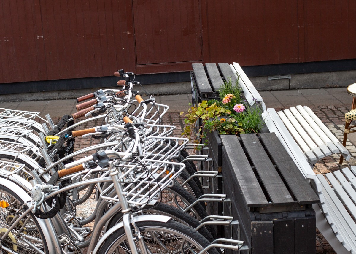 Cyklar på en sommarservering, ståendes bredvid två bänkar. Blommor blommar.