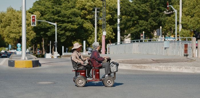 Två äldre personer på en gemensam permobil