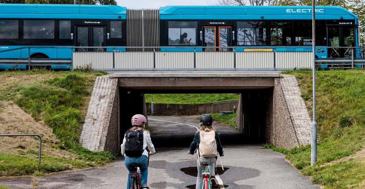två barn cyklar mot en gångtunnel